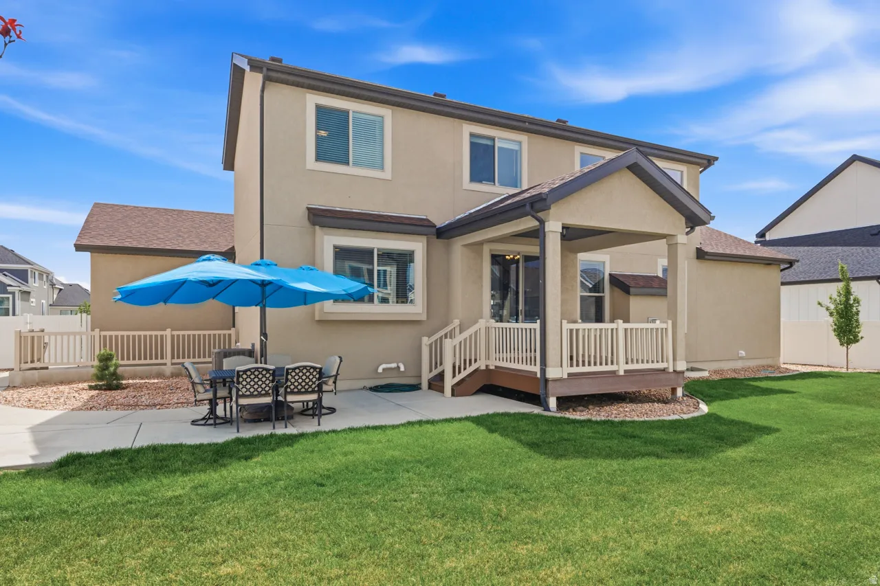 Rear view of house featuring a patio, stucco siding, a wooden deck, and outdoor dining area