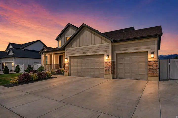 AI enhanced twilight. View of front facade with an attached garage, driveway, board and batten siding, and a gate