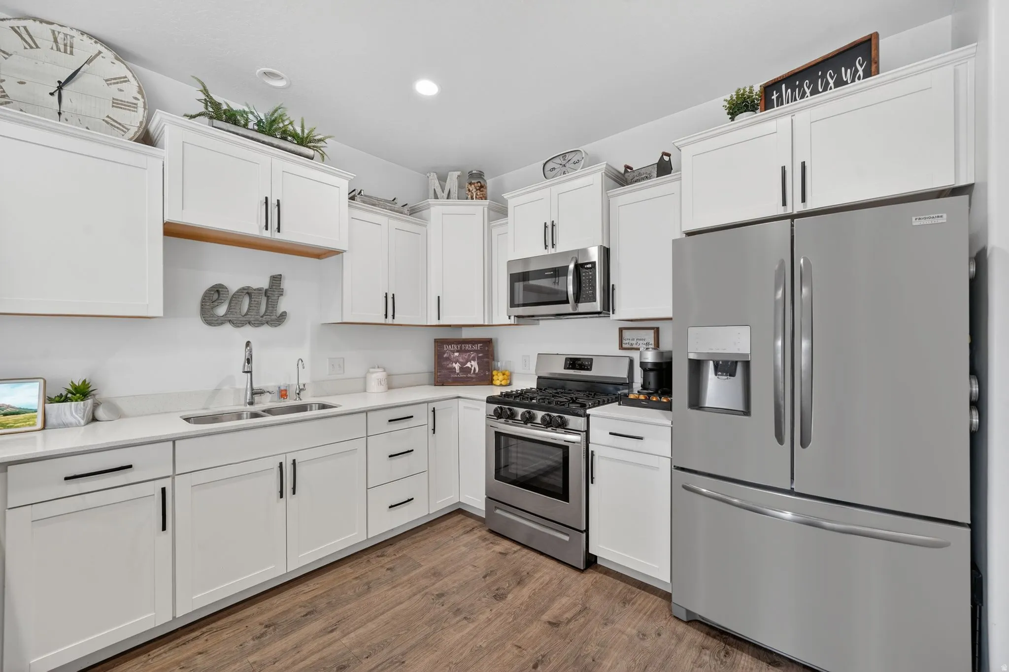 Kitchen with stainless steel appliances, white cabinetry, dark wood-style floors, light stone counters, and recessed lighting