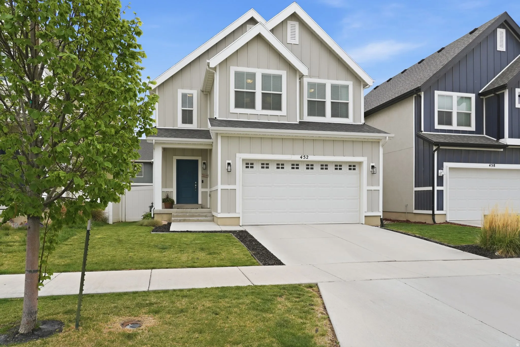 Craftsman-style home featuring board and batten siding, driveway, a garage, a front lawn, and roof with shingles