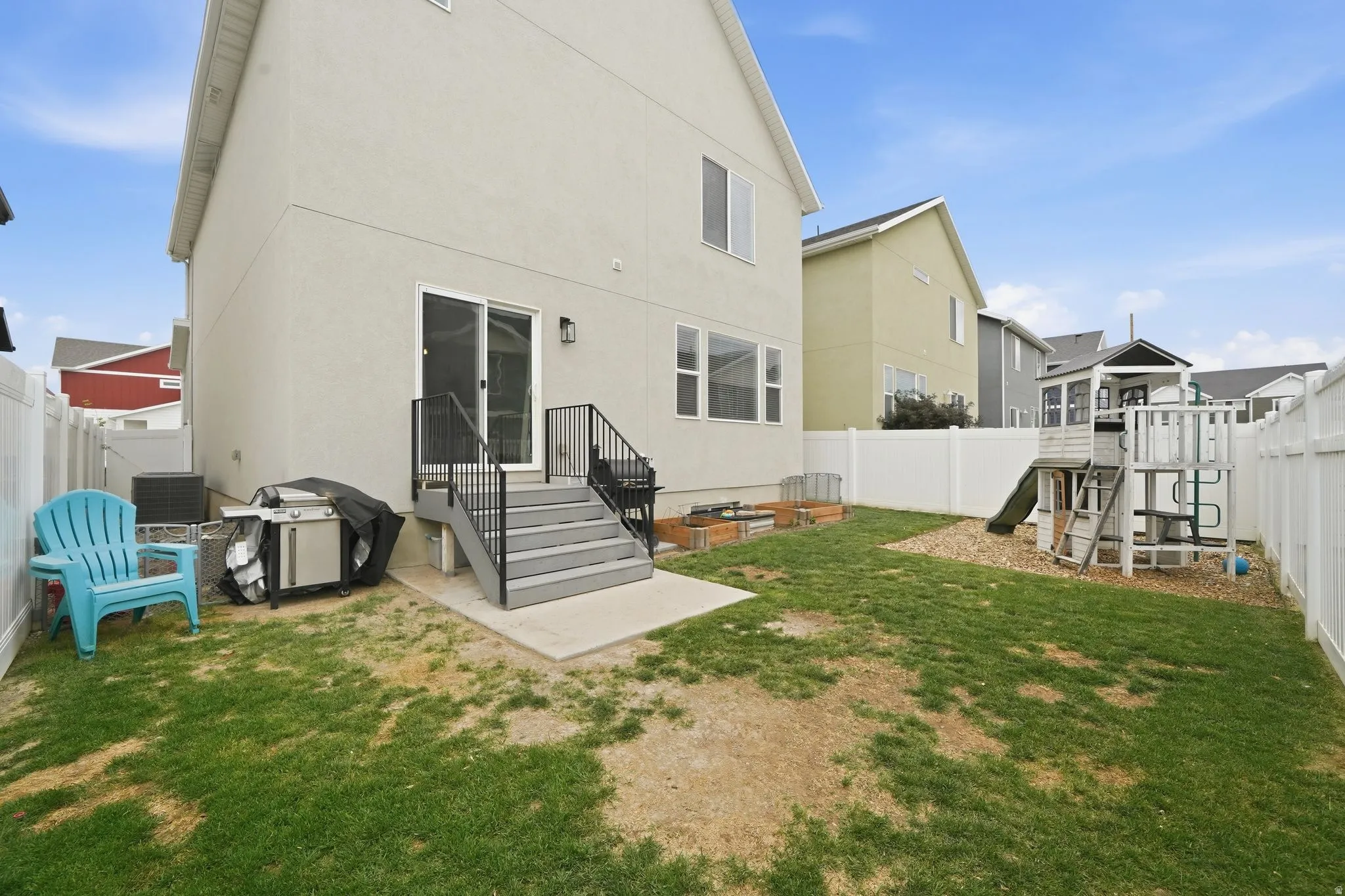 Back of house featuring a fenced backyard, stucco siding, a patio, and a playground