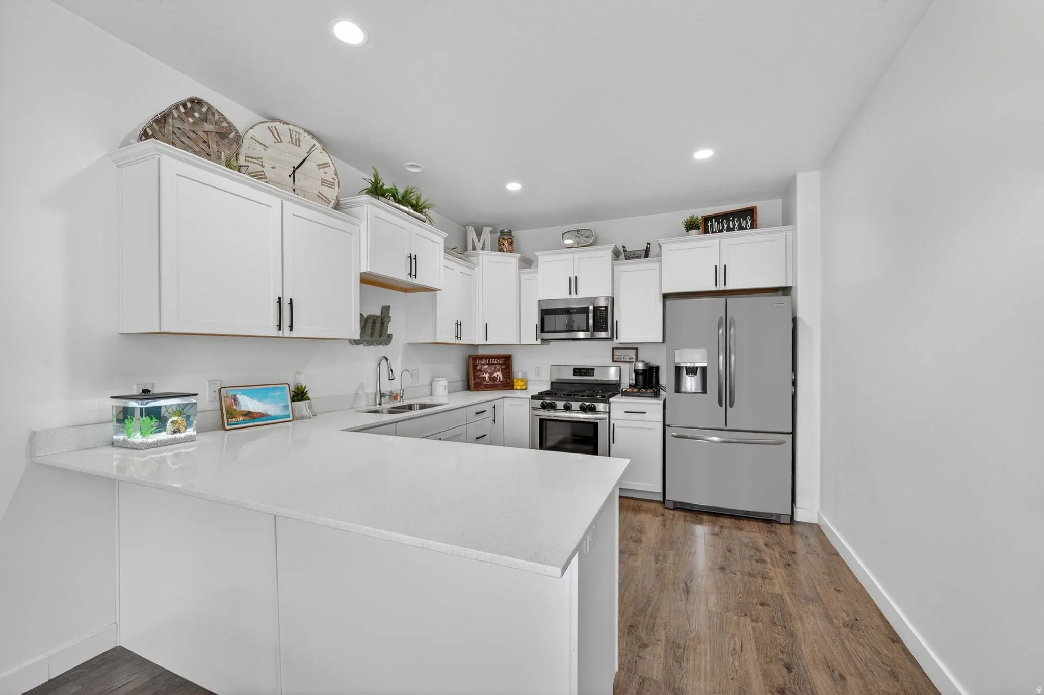 Kitchen featuring stainless steel appliances, white cabinets, a peninsula, dark wood-style floors, and recessed lighting