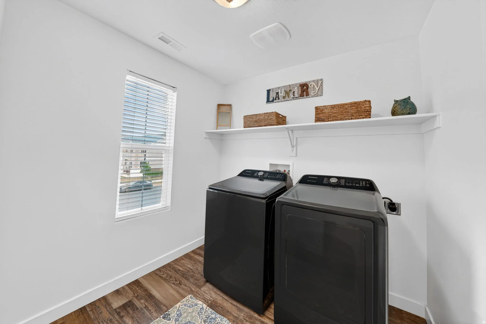 Laundry room with dark wood-type flooring and independent washer and dryer