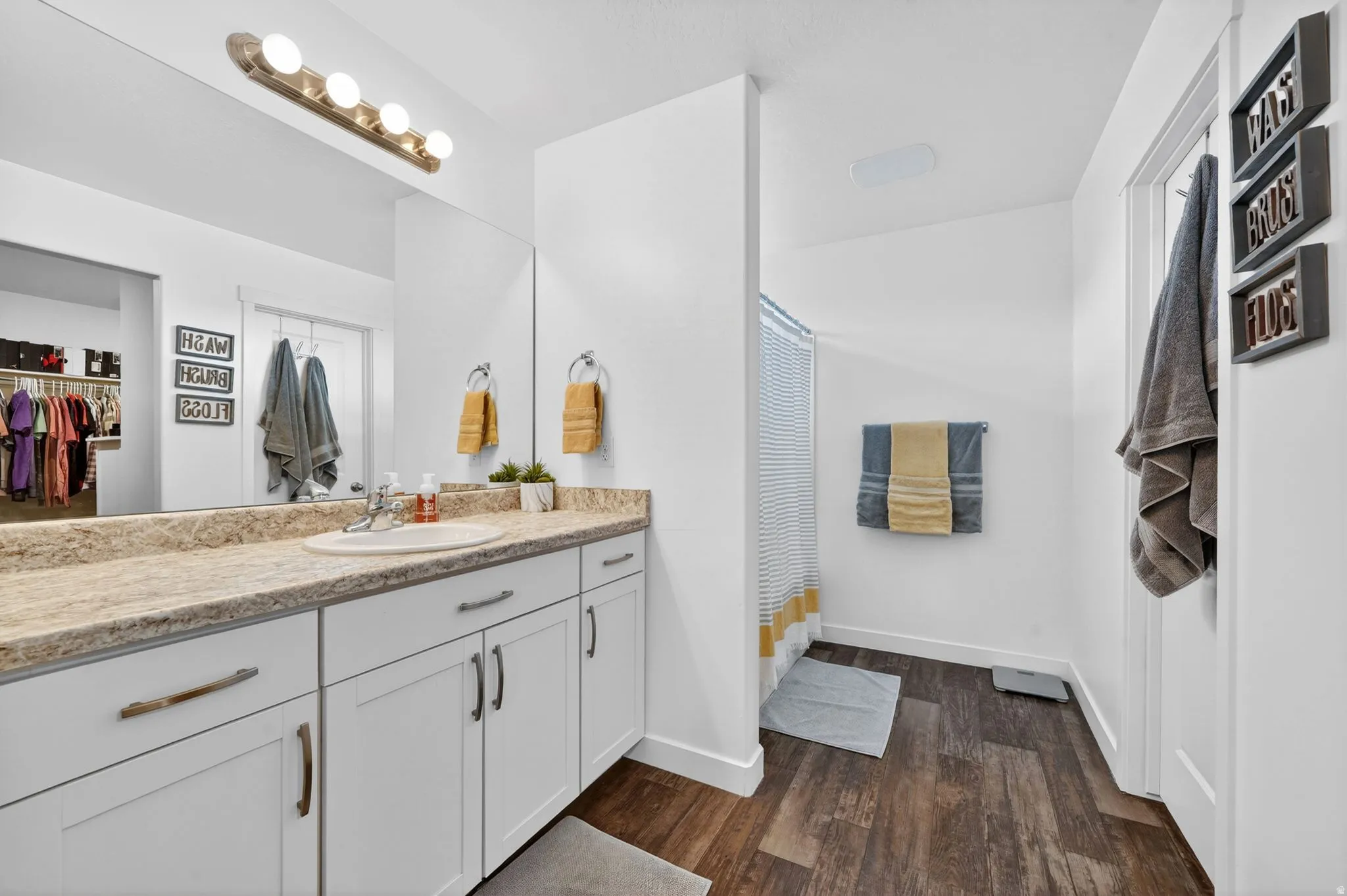 Bathroom featuring curtained shower, vanity, dark wood-style floors, and a walk in closet