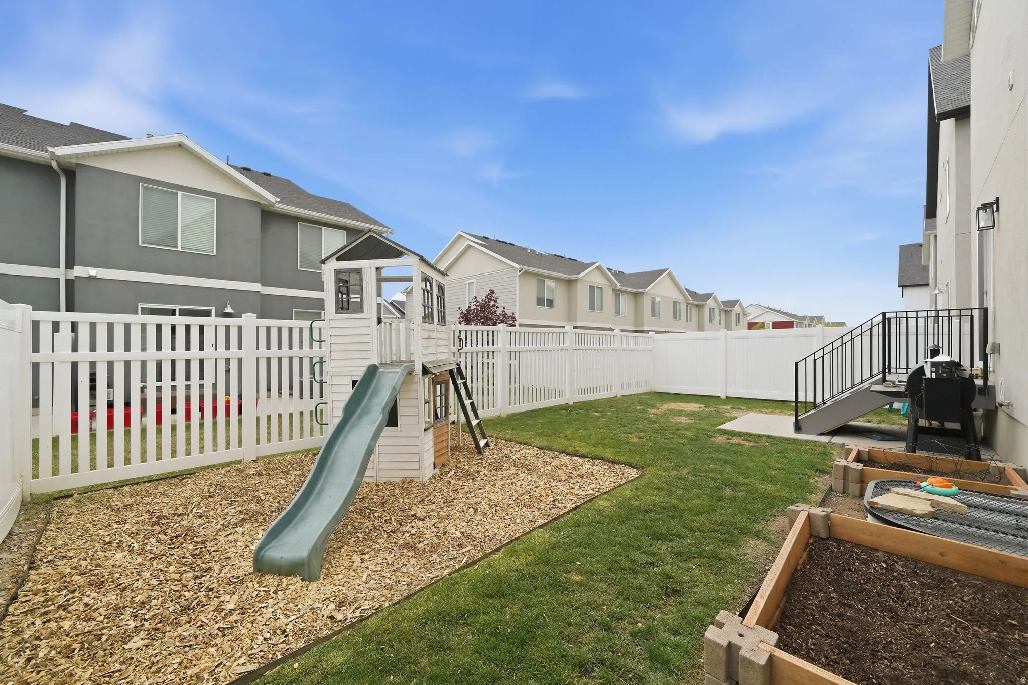 Fenced backyard with a residential view and a playground
