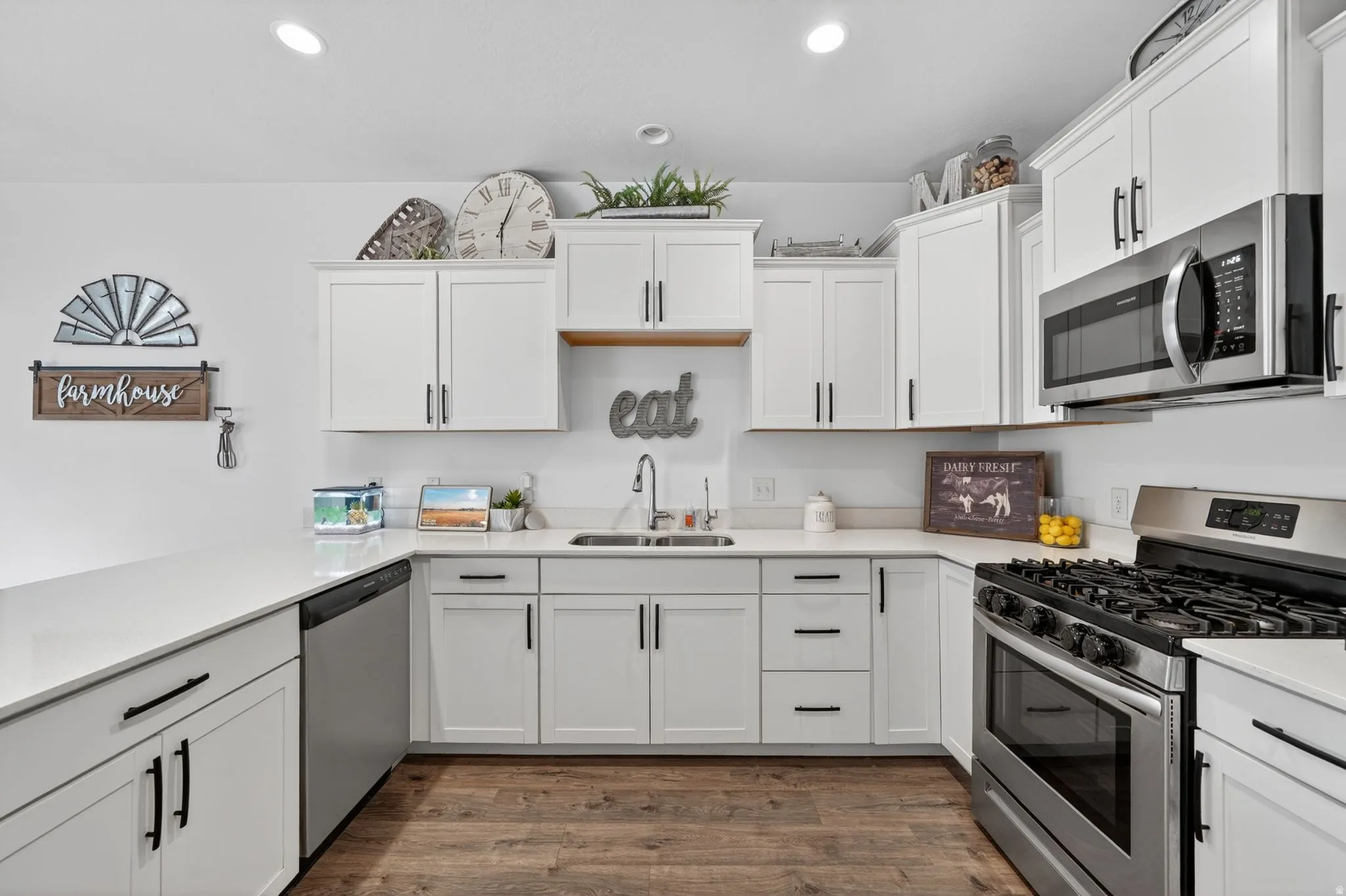 Kitchen featuring stainless steel appliances, white cabinetry, dark wood-style floors, recessed lighting, and light stone counters