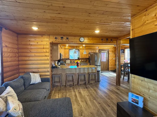Living room featuring log walls, wooden ceiling, recessed lighting, dark wood-type flooring, and plenty of natural light