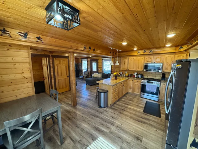Kitchen with stainless steel appliances, open floor plan, a peninsula, light wood-style floors, and hanging light fixtures