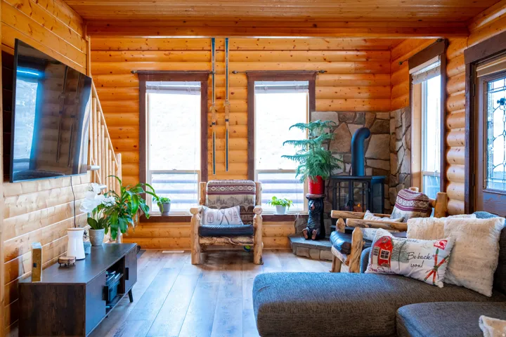 Living area featuring a wood stove, hardwood / wood-style flooring, log walls, and wood ceiling