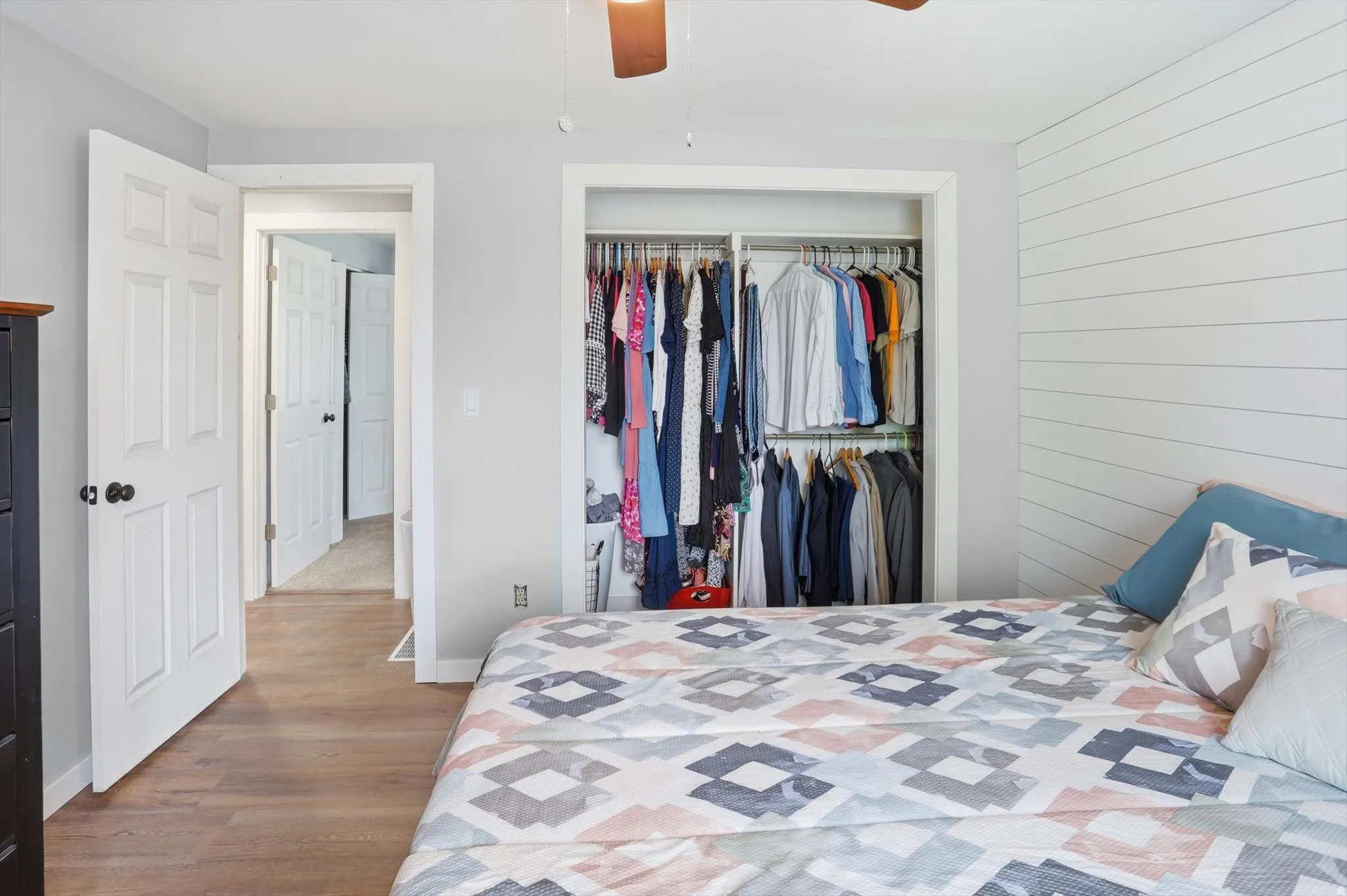 Bedroom with a closet, wood finished floors, ceiling fan, and wood walls