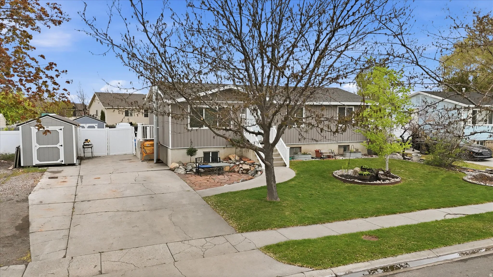View of front of home featuring a storage shed, concrete driveway, a gate, and a residential view
