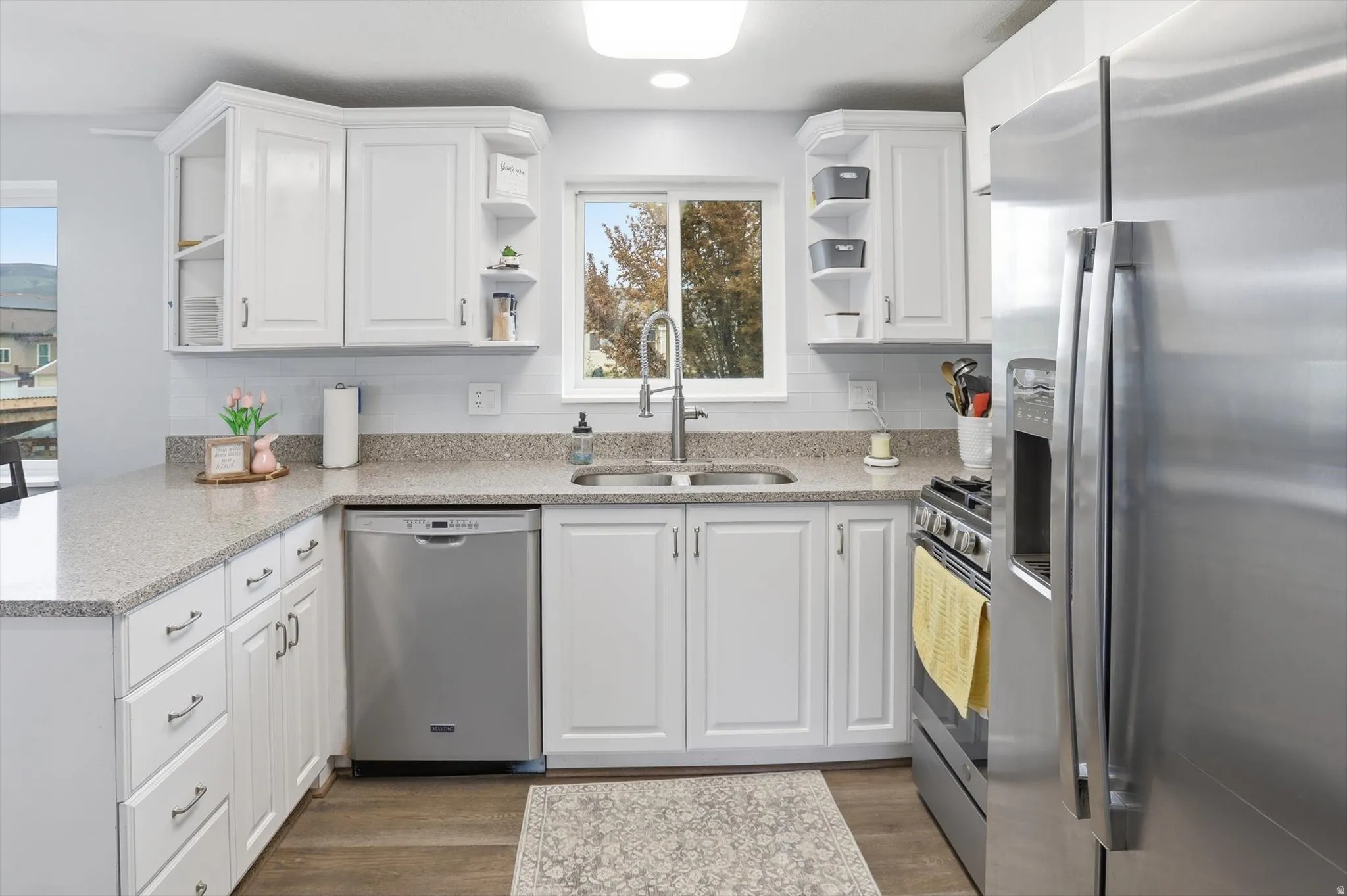 Kitchen featuring stainless steel appliances, open shelves, light stone countertops, white cabinetry, and light wood-style flooring