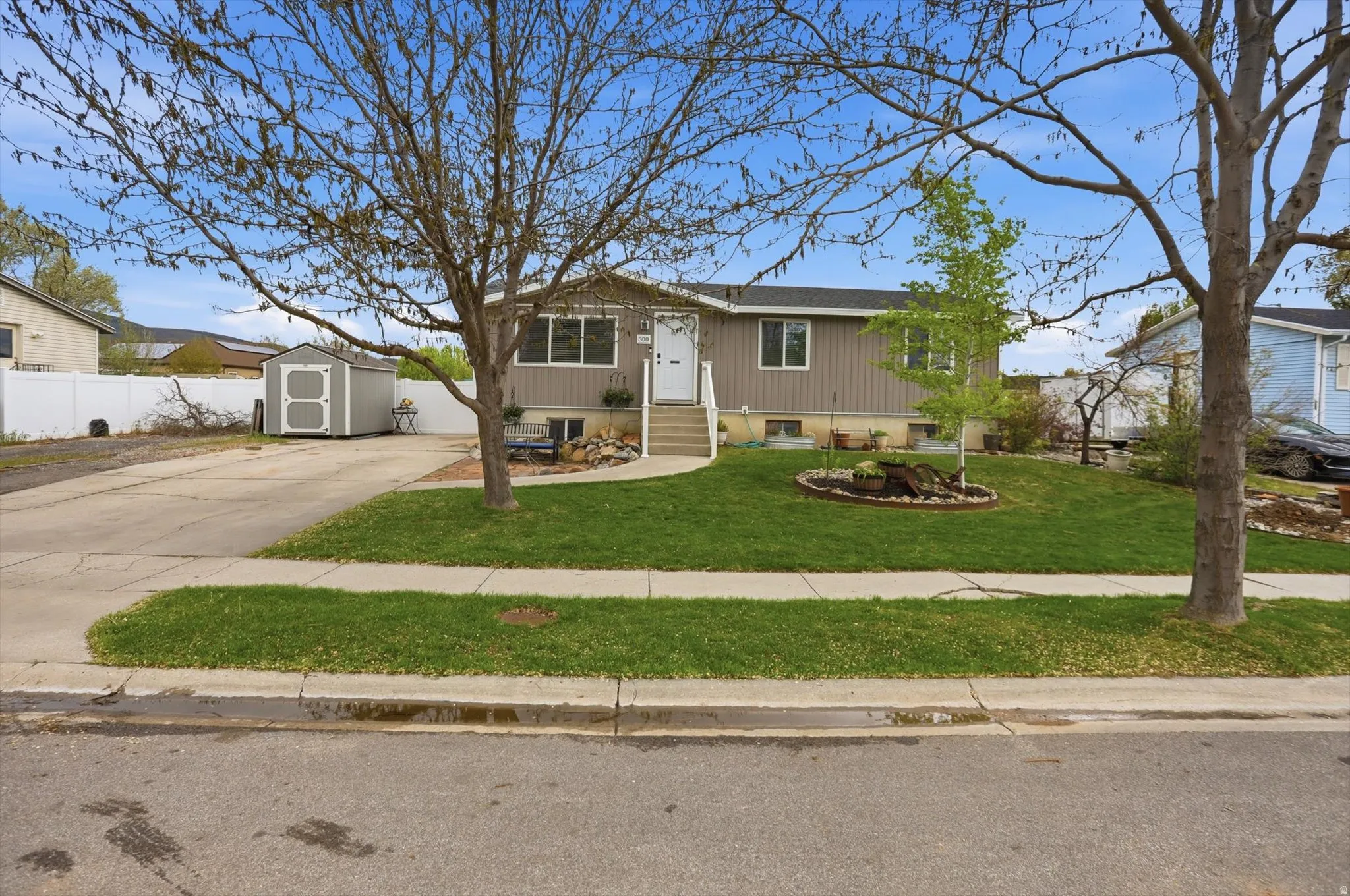 Ranch-style home with concrete driveway, a shed, and entry steps