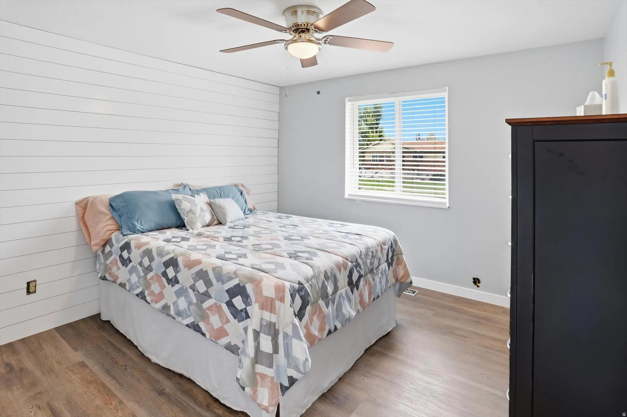 Bedroom with wooden walls, wood finished floors, and a ceiling fan