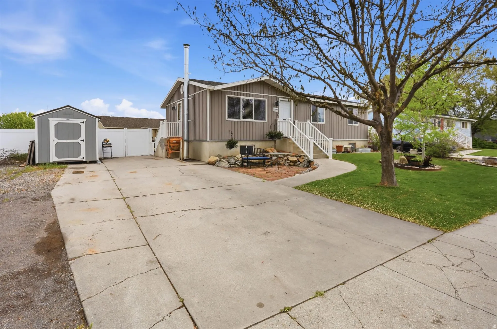 View of front of home with a storage shed, driveway, and a gate