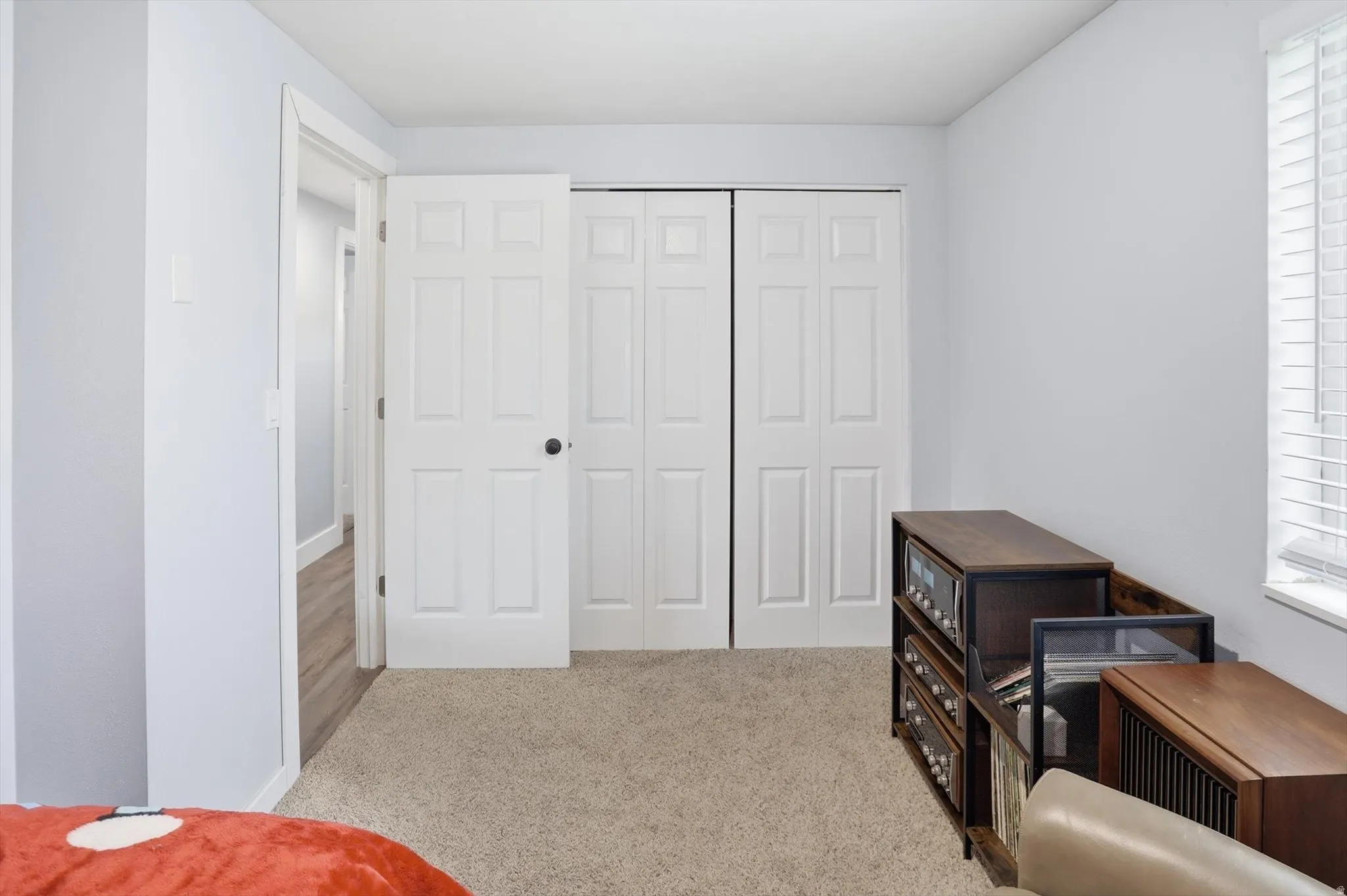 Bedroom with light colored carpet, multiple windows, and a closet