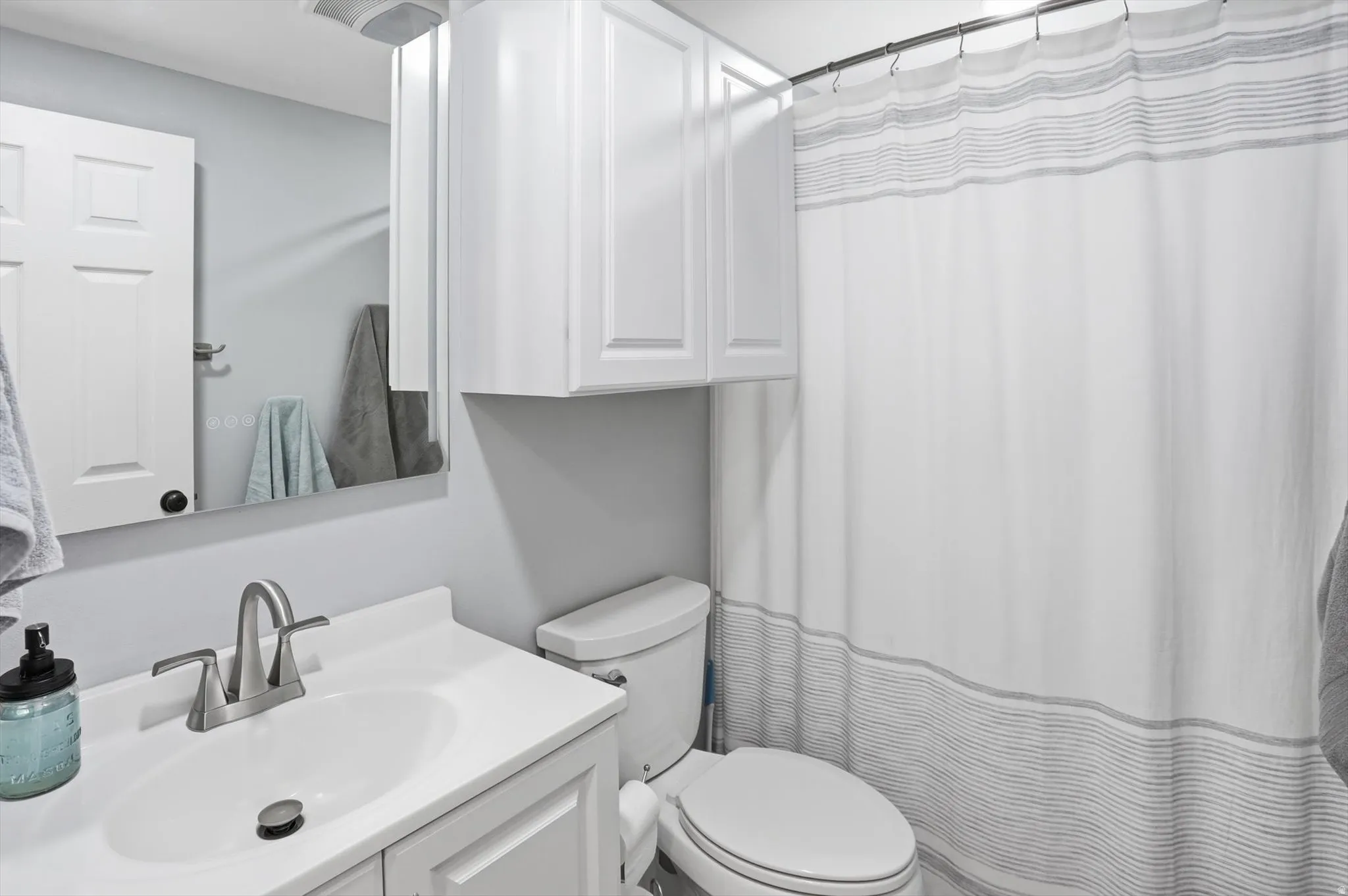Bathroom featuring curtained shower and vanity
