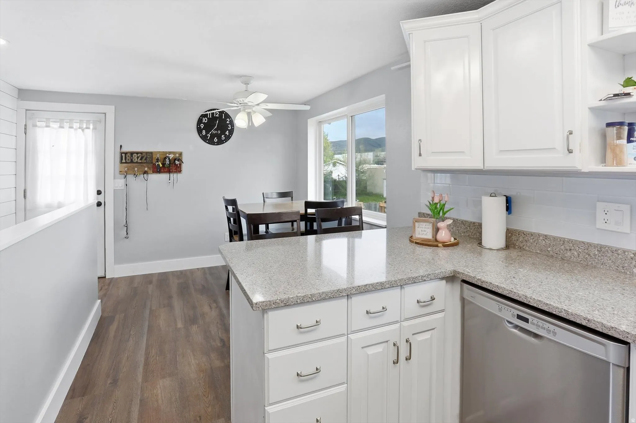 Kitchen featuring white cabinetry, dishwasher, a peninsula, and dark wood finished floors