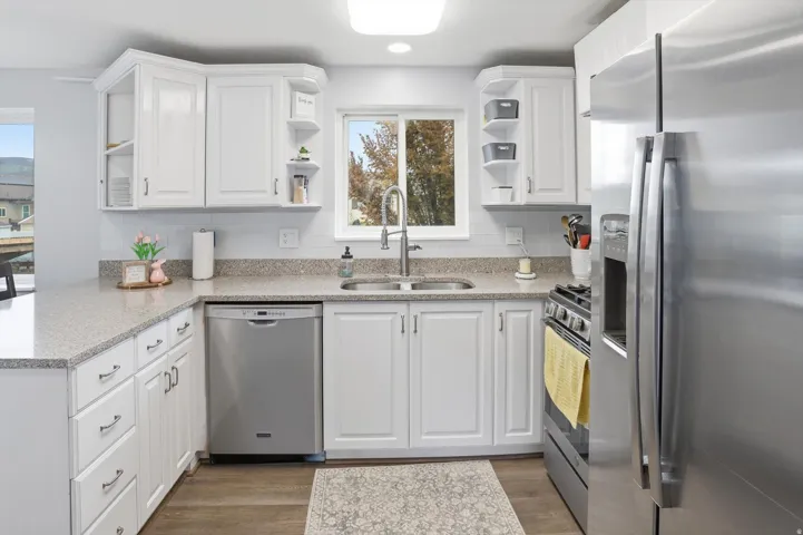 Kitchen featuring stainless steel appliances, open shelves, light stone countertops, white cabinetry, and light wood-style flooring