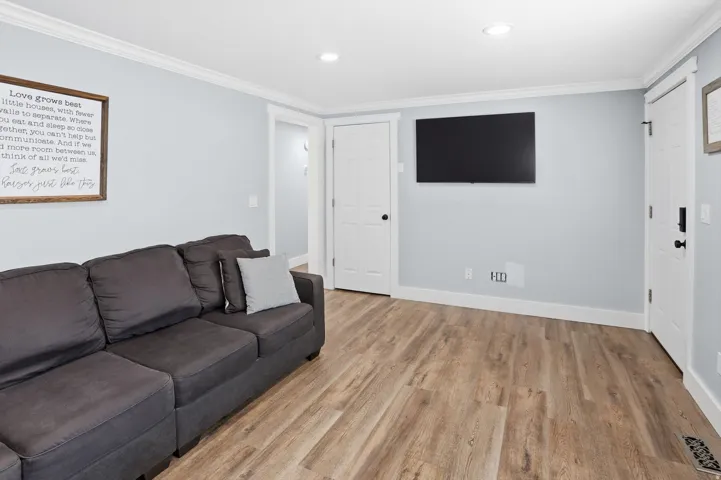 Living area featuring crown molding, light wood-style flooring, and recessed lighting