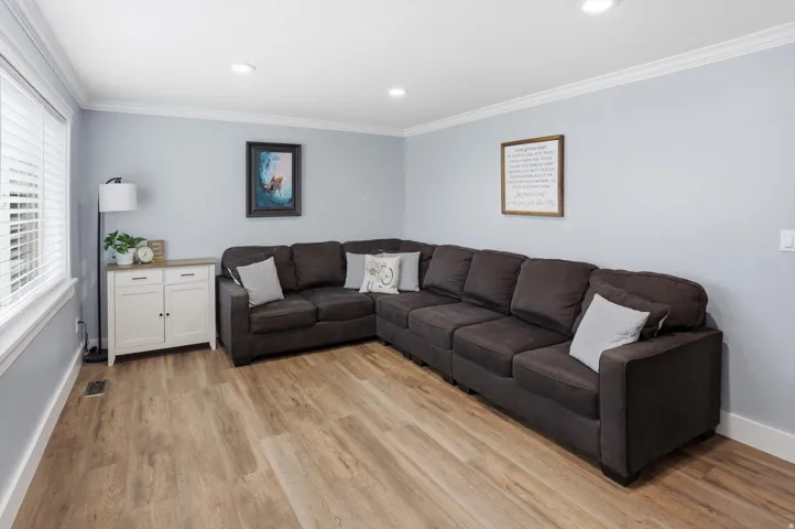 Living room with ornamental molding, light wood finished floors, and recessed lighting