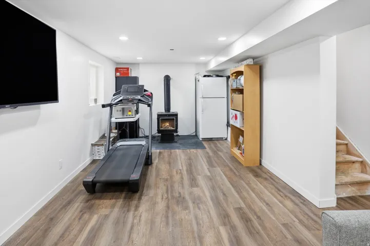 Exercise area with dark wood-type flooring, recessed lighting, and a wood stove