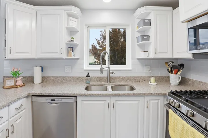 Kitchen featuring white cabinetry, open shelves, light stone countertops, stainless steel appliances, and backsplash