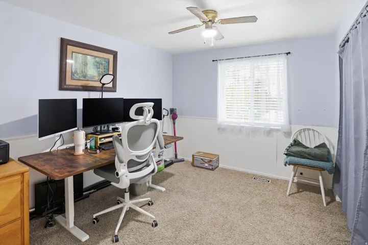 Office with light carpet, a ceiling fan, and a wainscoted wall