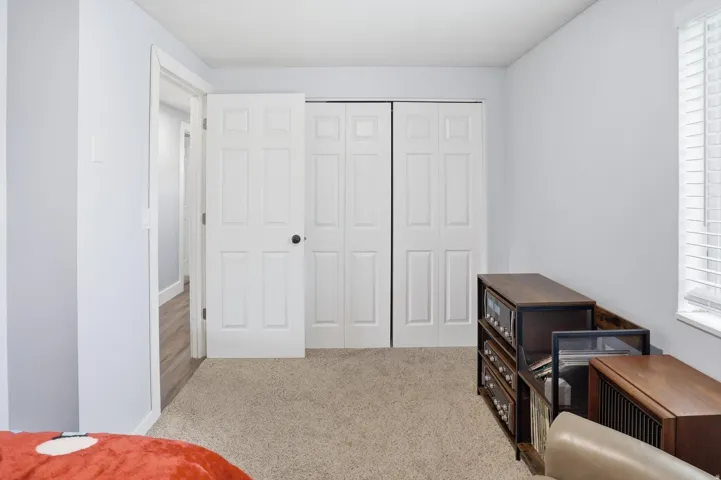 Bedroom with light colored carpet, multiple windows, and a closet