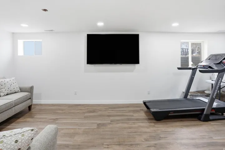 Exercise room with light wood finished floors and recessed lighting