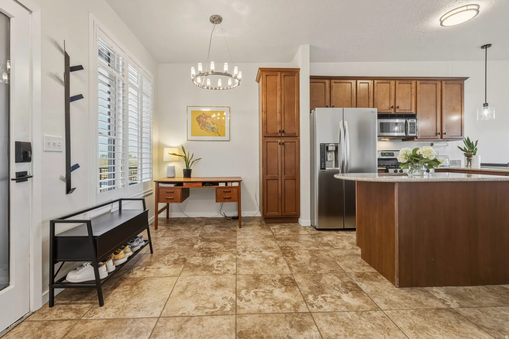 Kitchen with wood finish cabinets, stainless steel appliances, light stone counters, and hanging lights