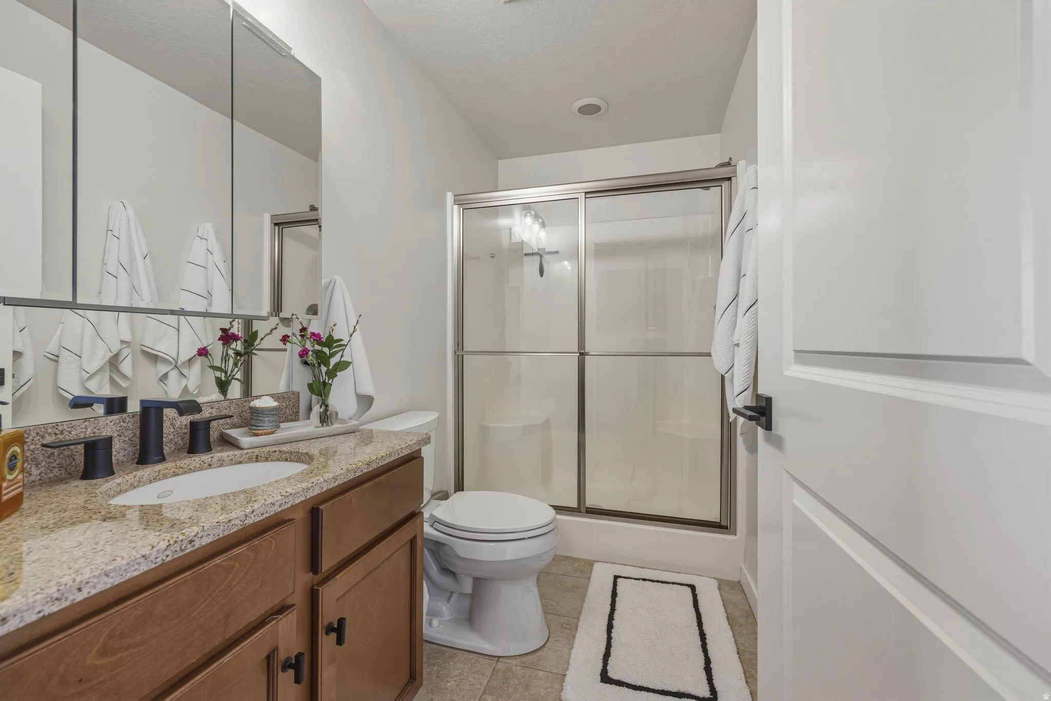 Full bathroom featuring vanity, a stall shower, and light tile patterned flooring