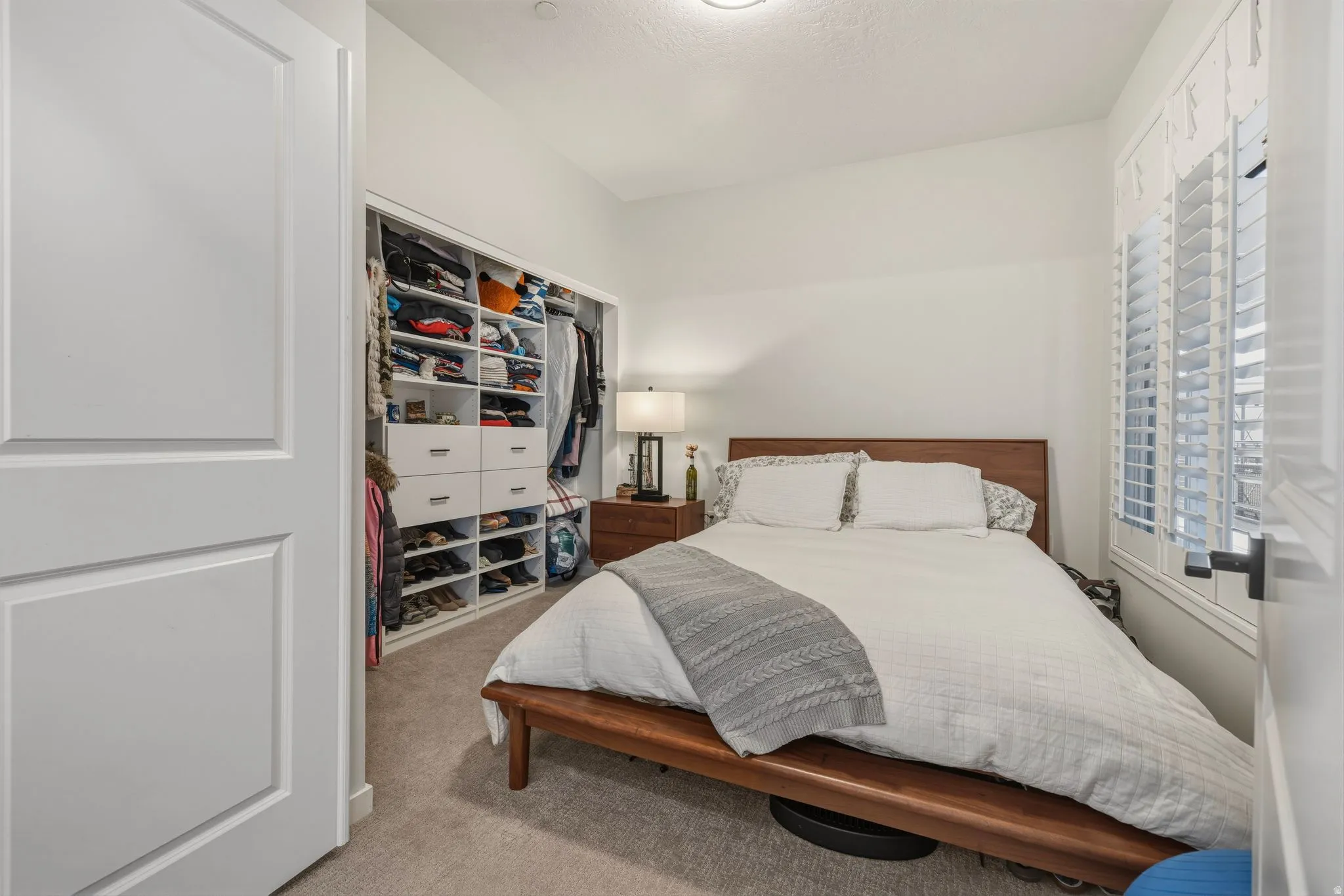Bedroom with light colored carpet and a closet