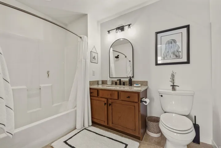 Full bath featuring vanity, shower / bathtub combination with curtain, and light tile patterned floors