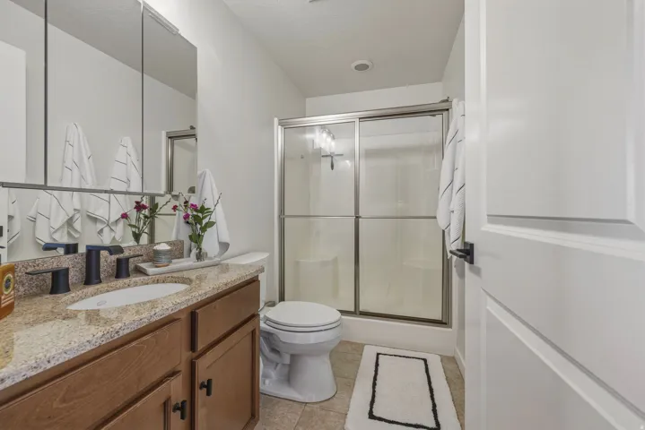 Full bathroom featuring vanity, a stall shower, and light tile patterned flooring