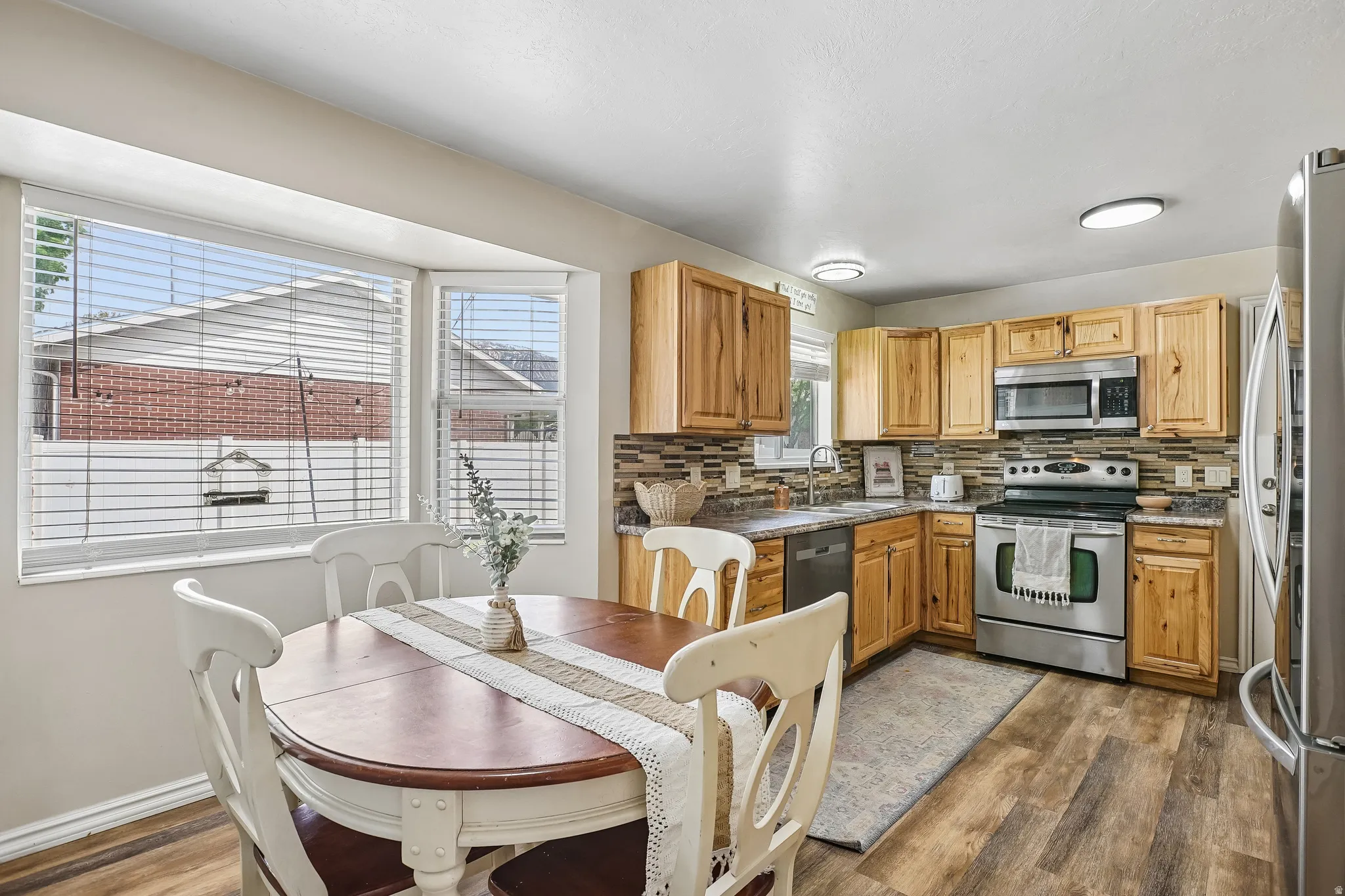 Kitchen featuring dark wood-style flooring, stainless steel appliances, and backsplash
