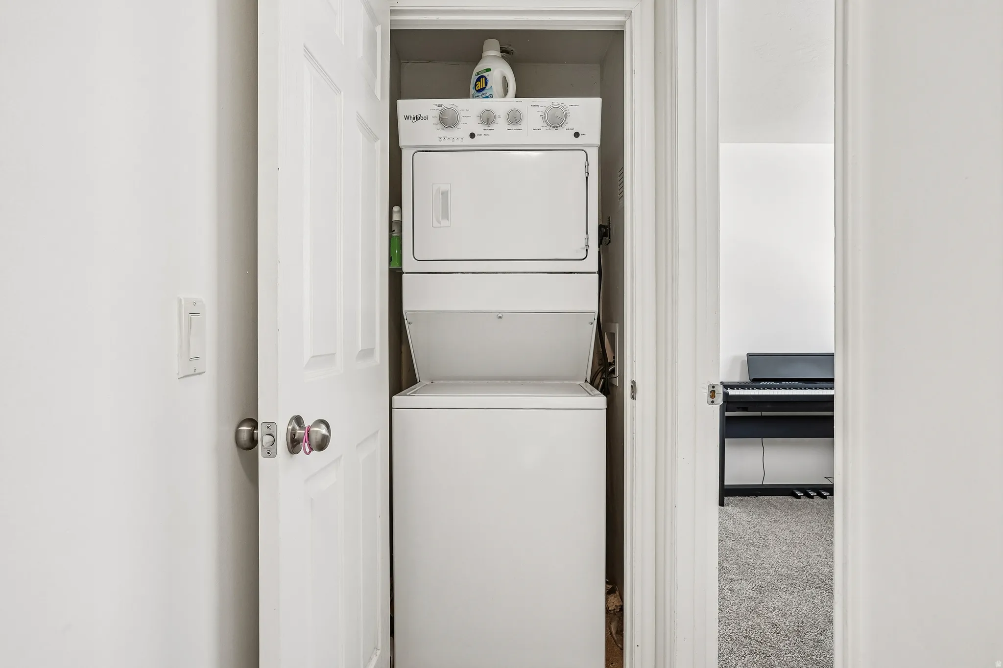 Laundry area with stacked washer and clothes dryer and carpet floors