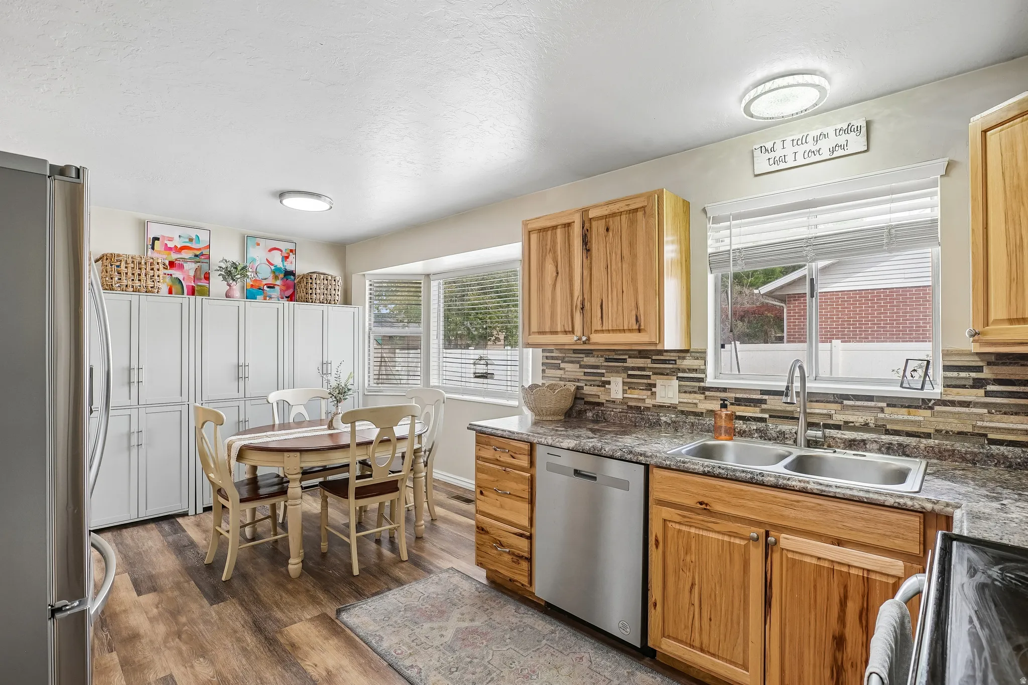 Kitchen featuring stainless steel appliances, dark wood-type flooring, and tasteful backsplash