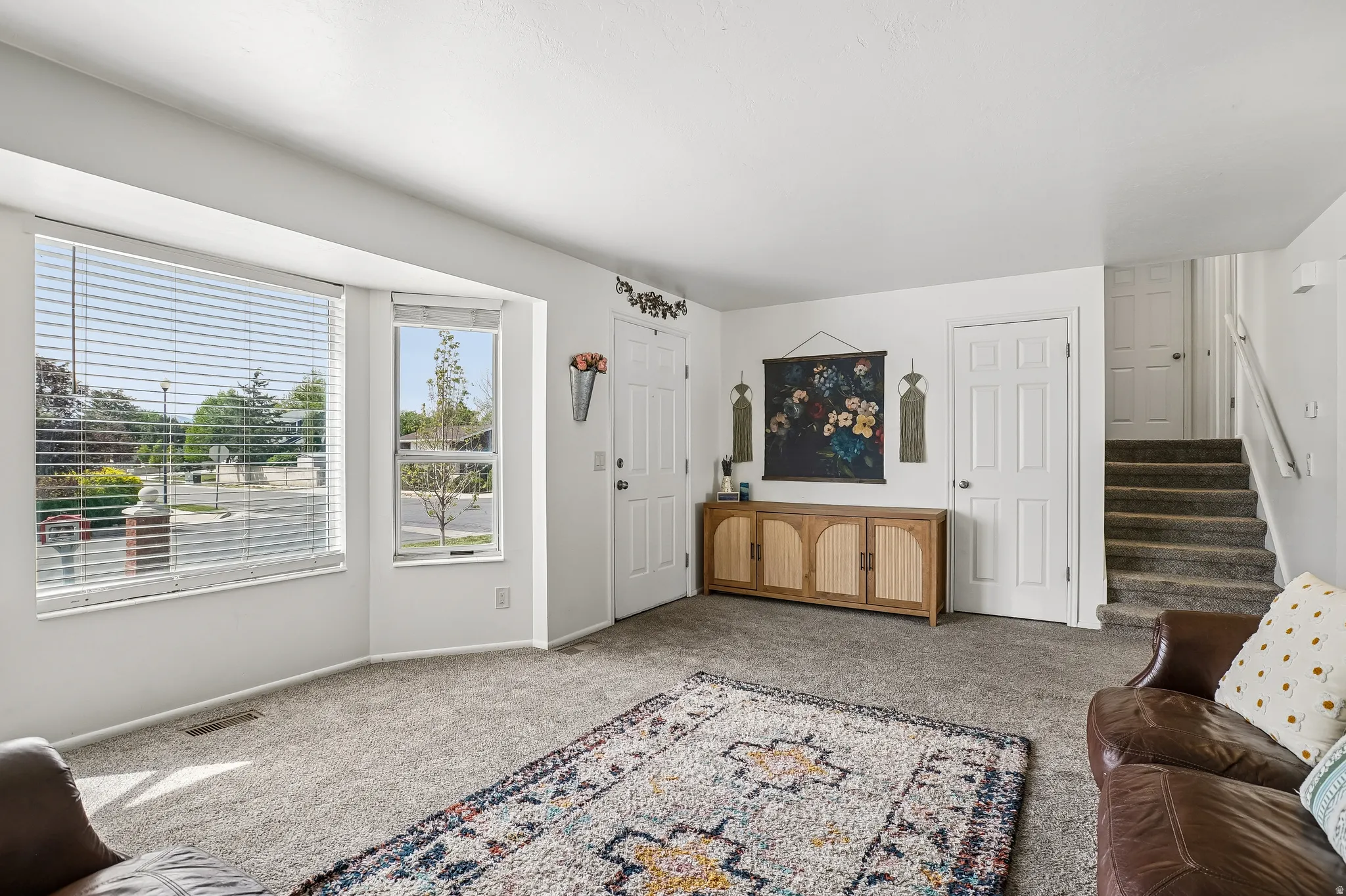 Carpeted living room featuring stairway and baseboards