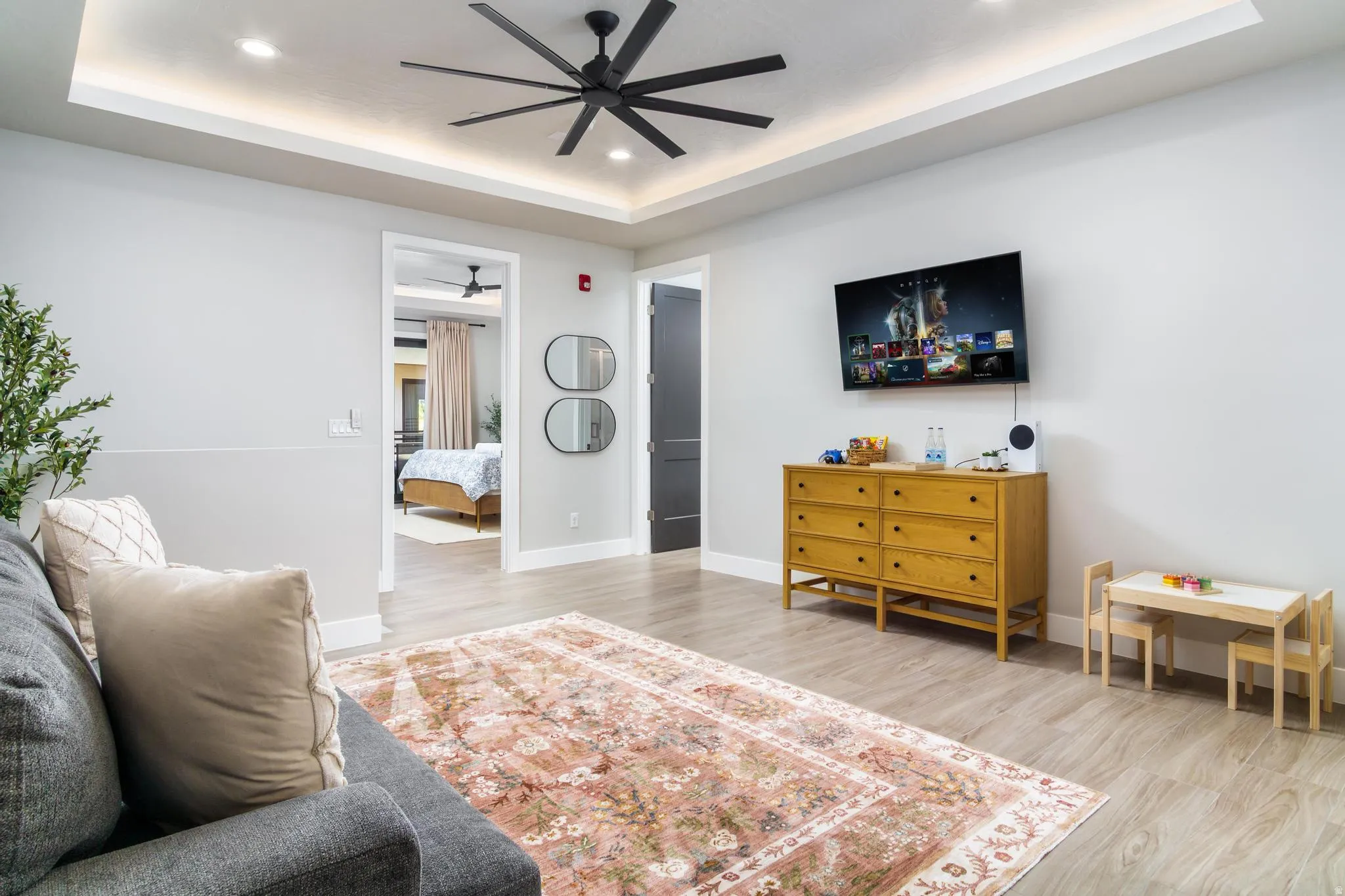 Living area featuring light wood finished floors, recessed lighting, and a raised ceiling