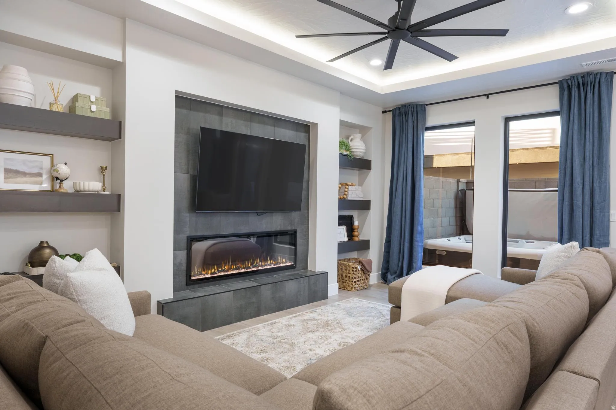 Living room featuring built in features, ceiling fan, a tiled fireplace, wood finished floors, and recessed lighting