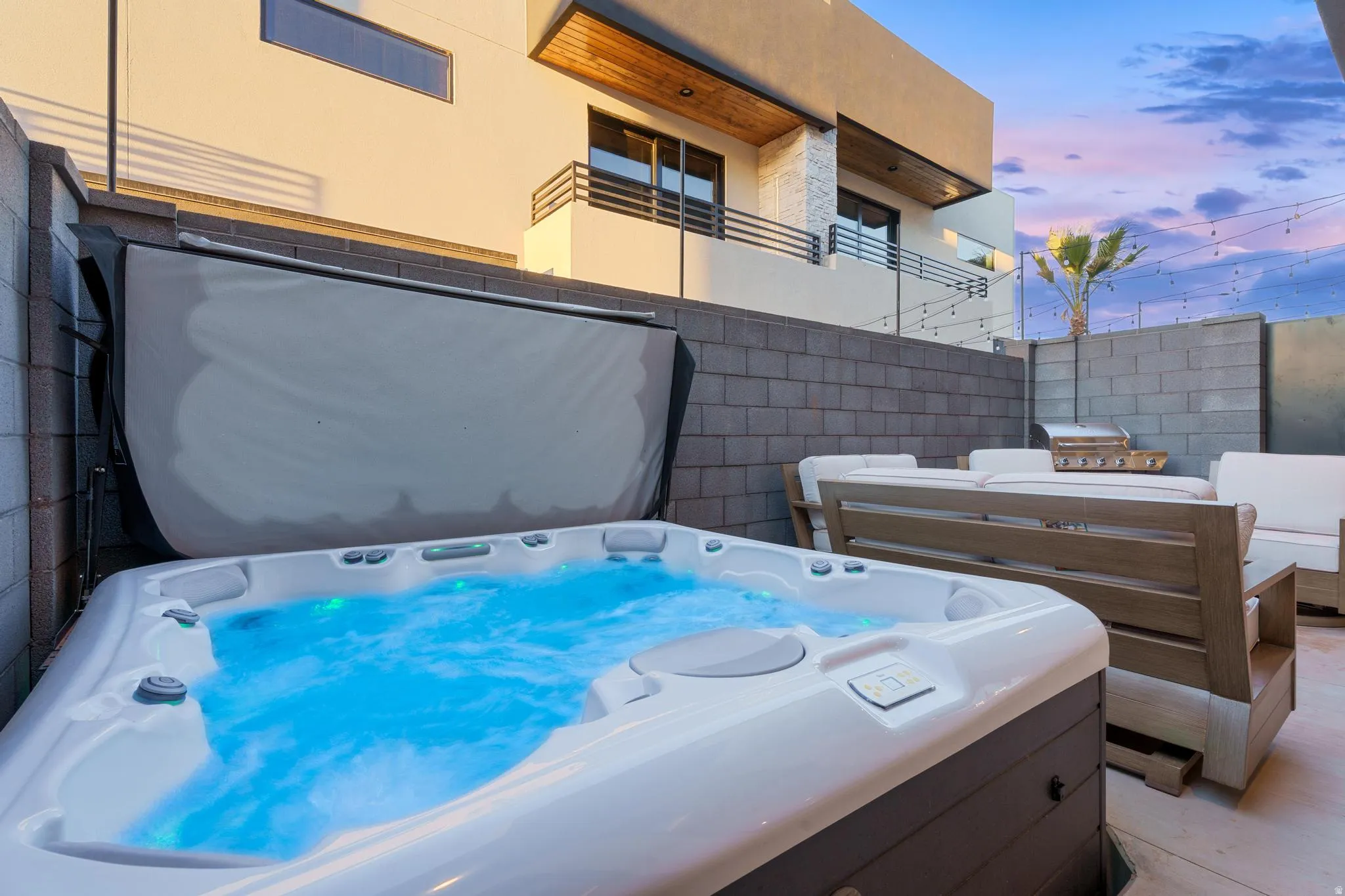 Patio terrace at dusk featuring a hot tub and a balcony