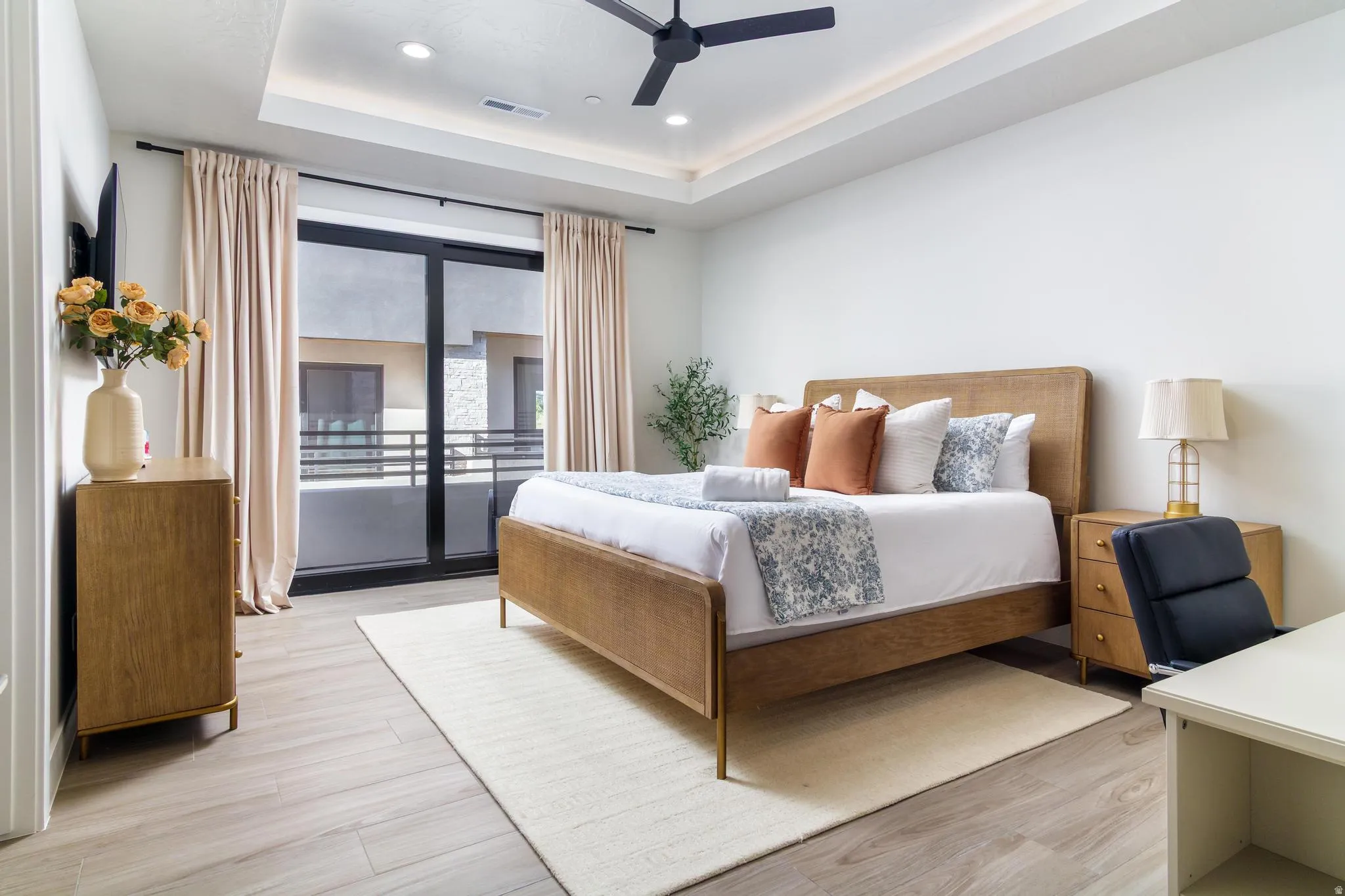 Bedroom with access to exterior, light wood-style floors, recessed lighting, ceiling fan, and a tray ceiling