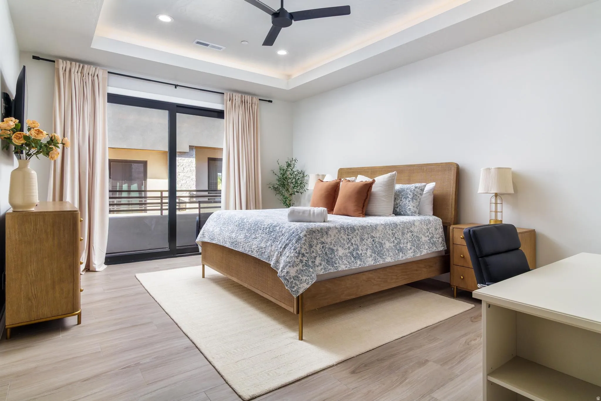 Bedroom featuring access to exterior, light wood-style flooring, recessed lighting, a ceiling fan, and a tray ceiling