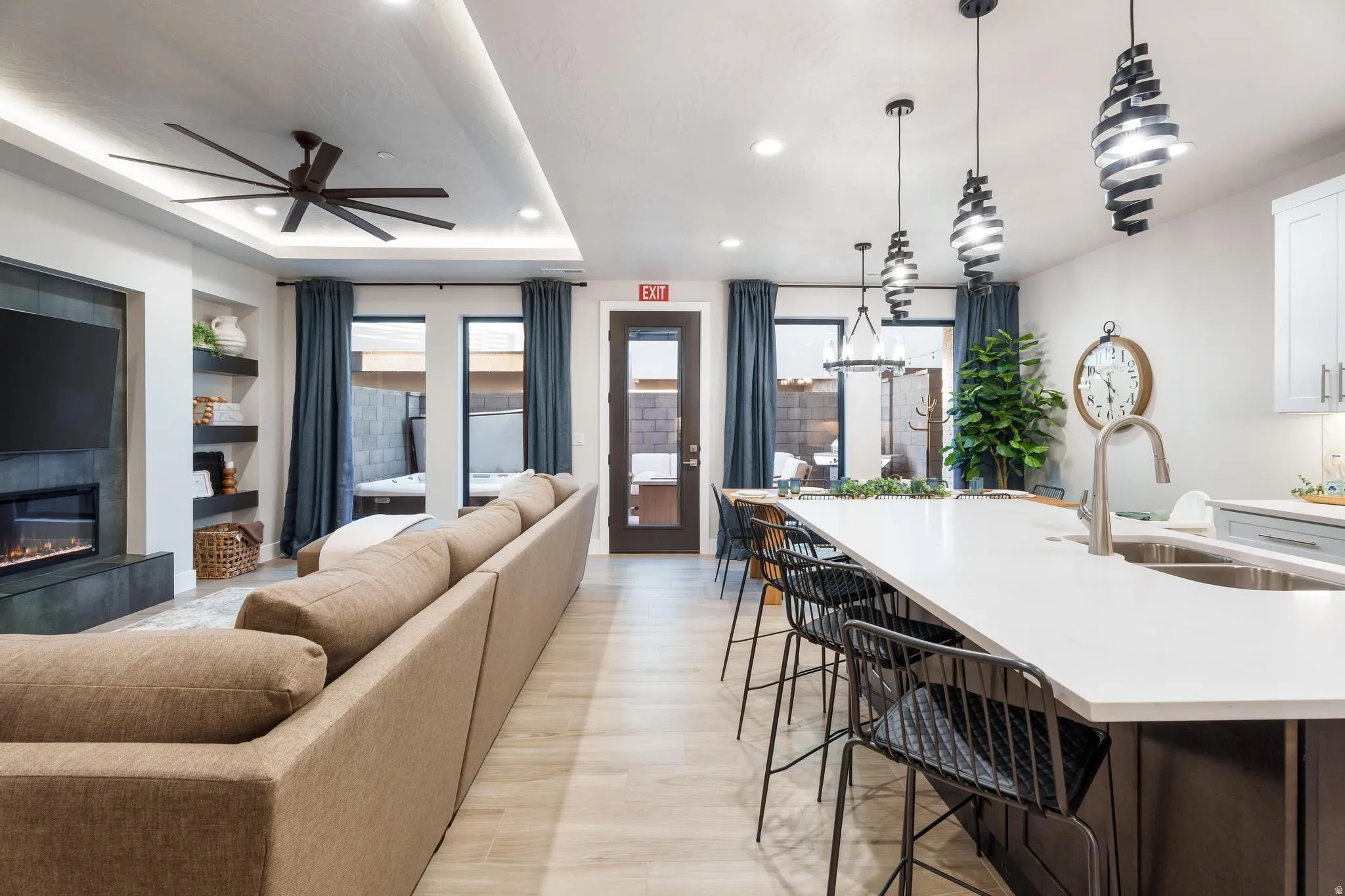 Living room featuring recessed lighting, ceiling fan, a glass covered fireplace, and a tray ceiling