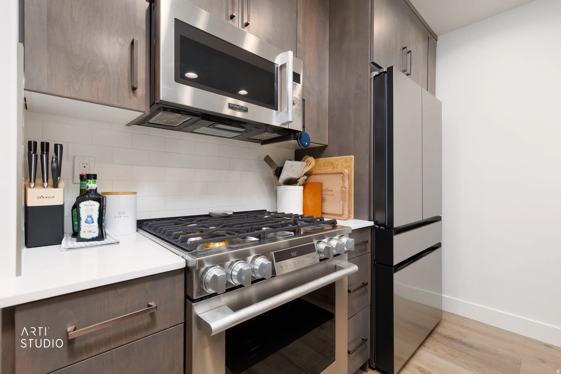 Kitchen with stainless steel appliances, dark wood finish cabinets, modern cabinets, and tasteful backsplash