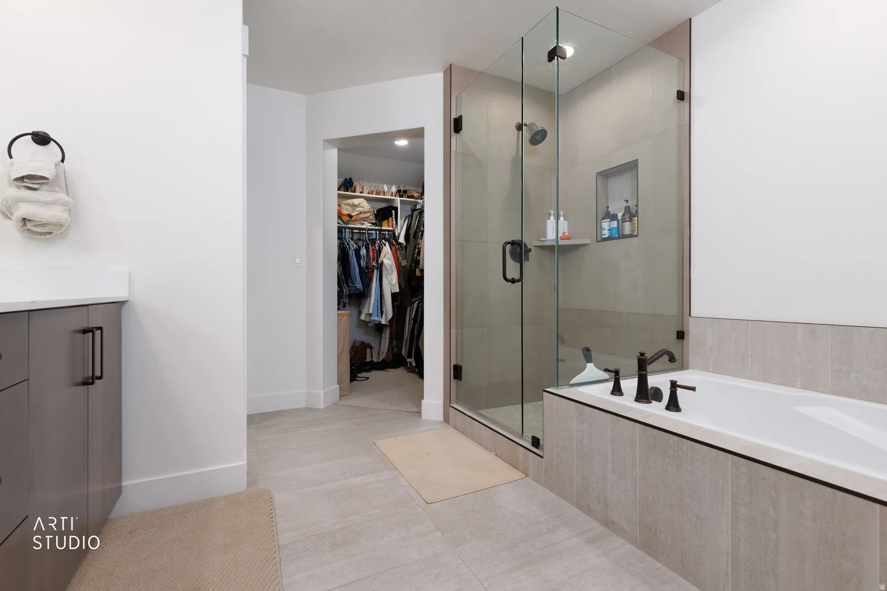 Full bath with a walk in closet, a garden tub, vanity, a shower stall, and light tile patterned floors