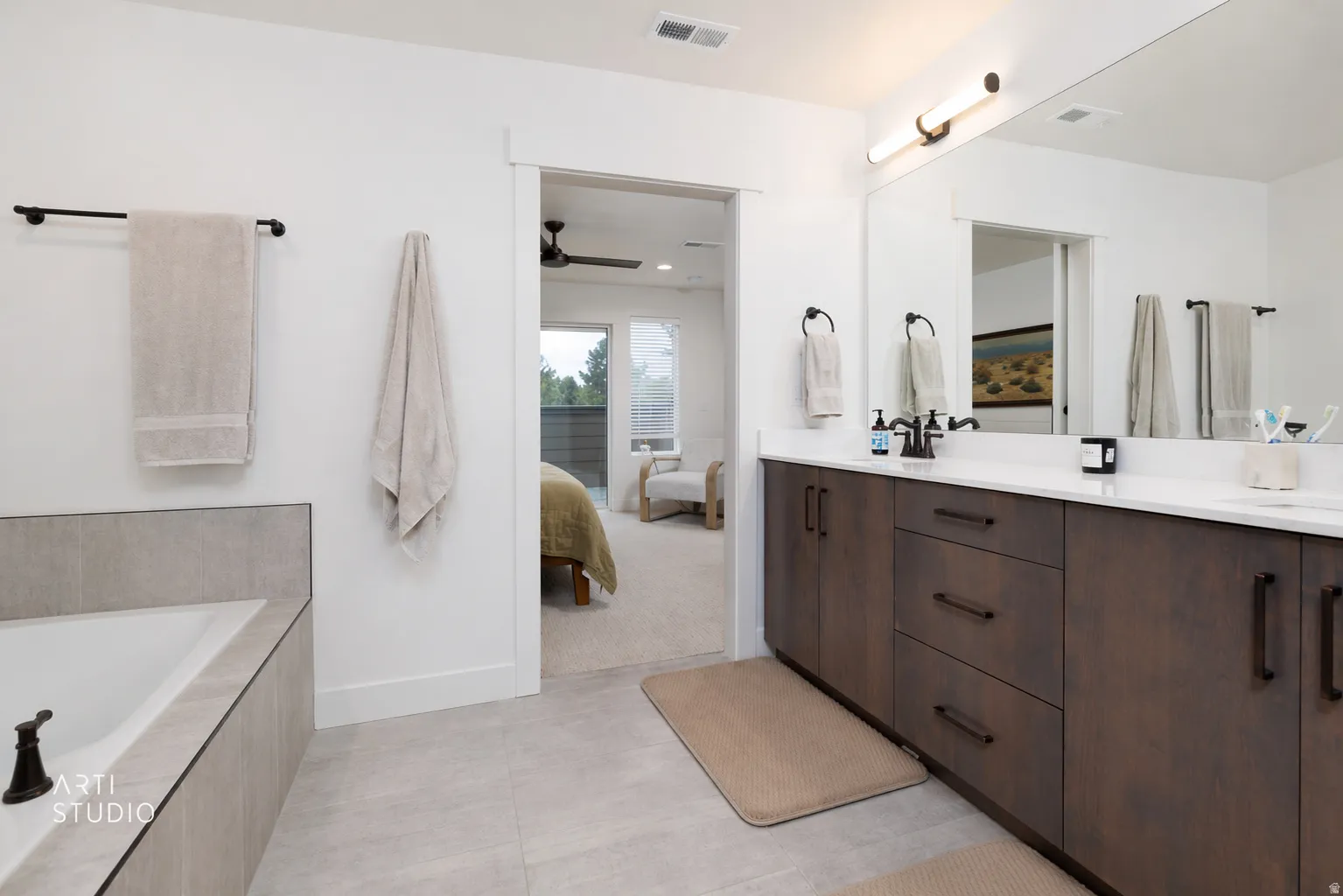 Bathroom with ensuite bathroom, double vanity, a garden tub, light tile patterned floors, and a ceiling fan