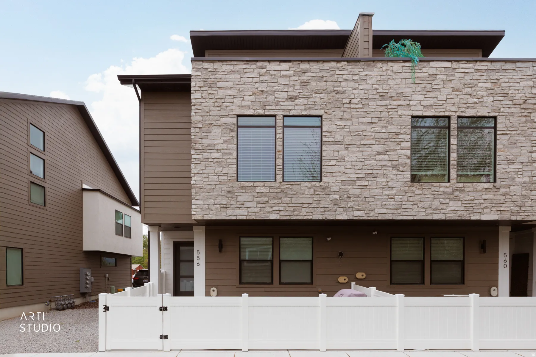 View of front of property featuring stone siding, a fenced front yard, and a gate