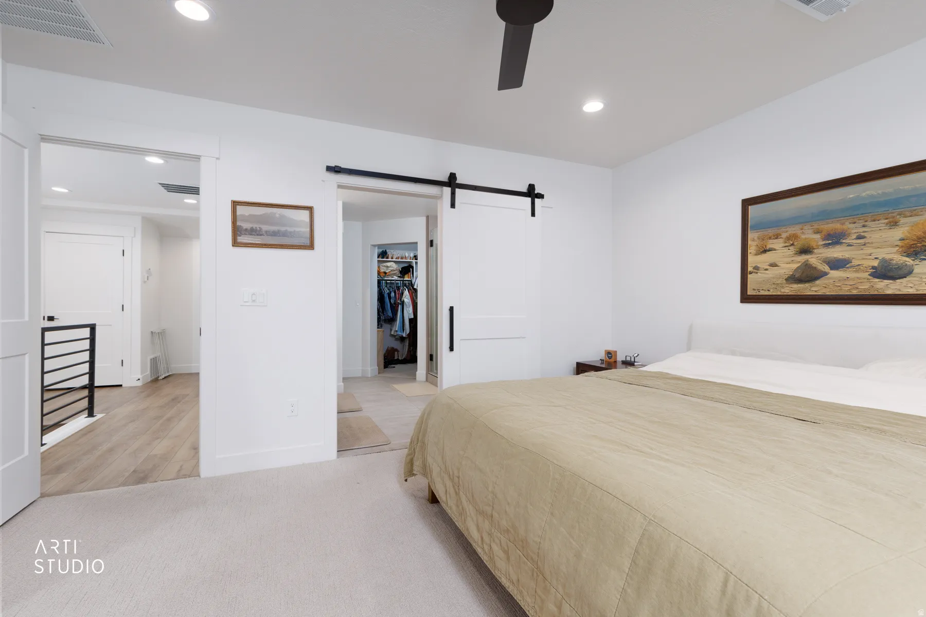 Bedroom with a barn door, light carpet, a walk in closet, recessed lighting, and a ceiling fan
